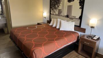 Een hotelkamer met een bed, nachtlampjes, een nachtkastje en een grote spiegel.