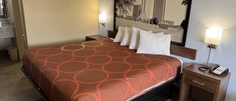 Una habitación de hotel con cama, lámparas de noche, mesita de noche y un espejo grande.