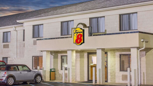 Un hotel Super 8 con estacionamiento y un automóvil estacionado al frente.