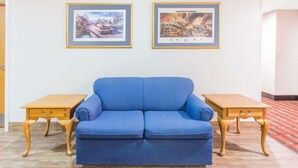 Un sofá azul con mesitas de madera, dos cuadros en la pared y una alfombra estampada.
