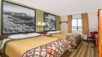 A hotel room with two beds, a large window with curtains, and two framed black and white landscape pictures on the wall.