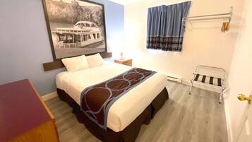 A bedroom with a bed, a nightstand, a window with curtains, a framed picture on the wall, and a door with a golden handle.