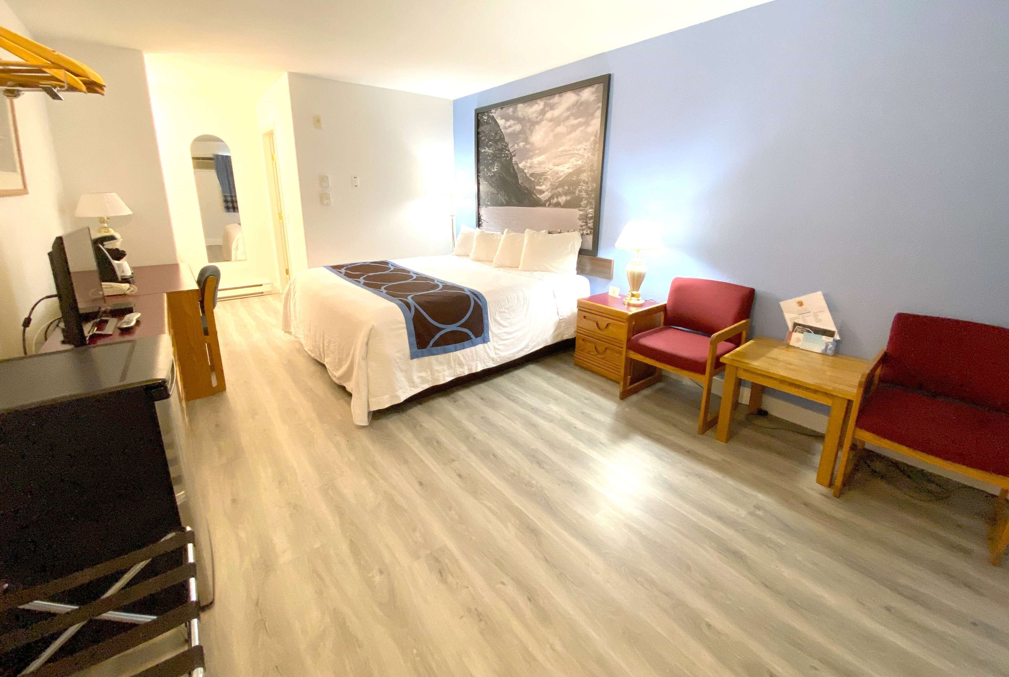 Een hotelkamer met een bed, een bureau, een stoel en een klein tafeltje.