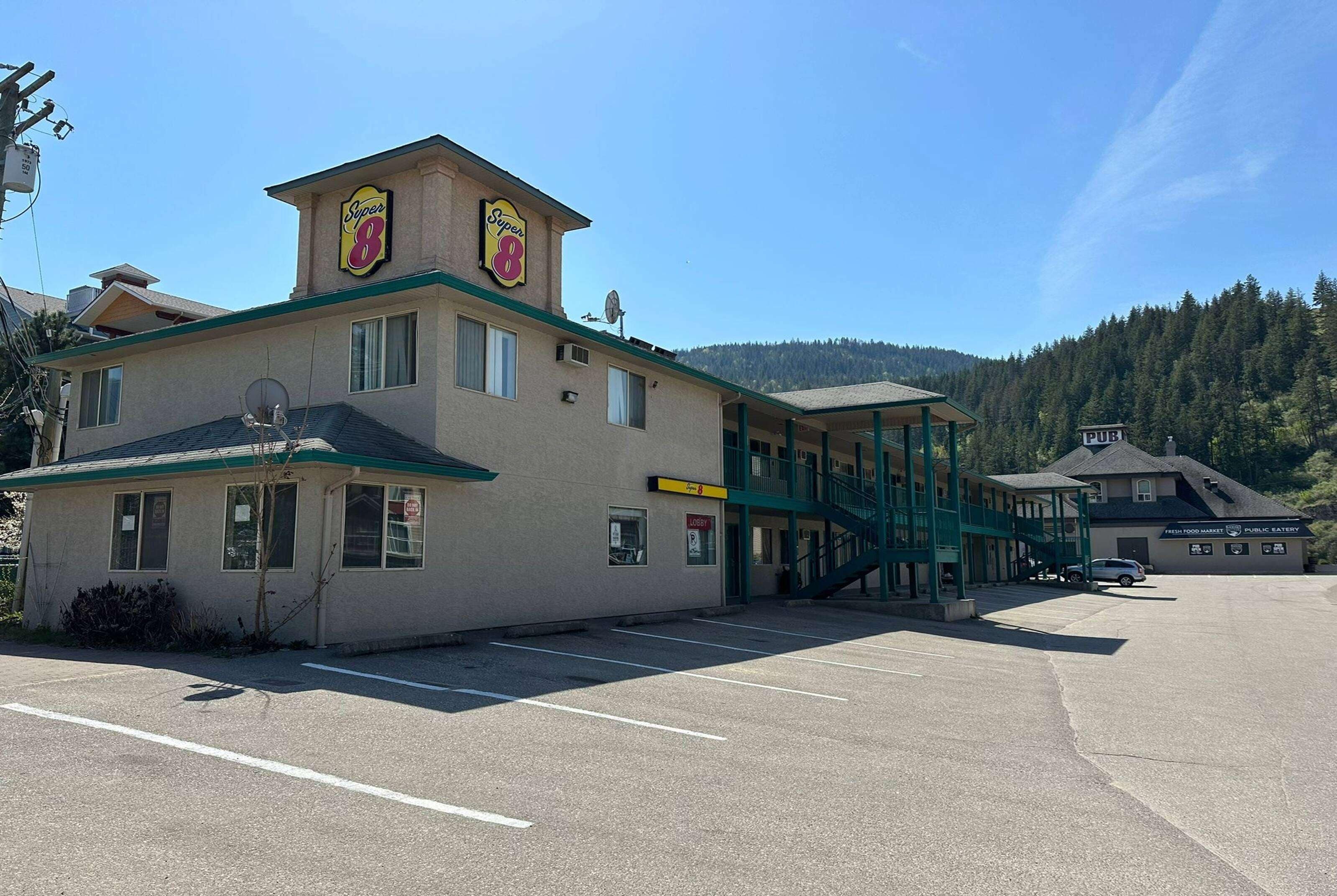 A building with a prominent 'Super 8' sign, a covered outdoor area, and a parking lot.