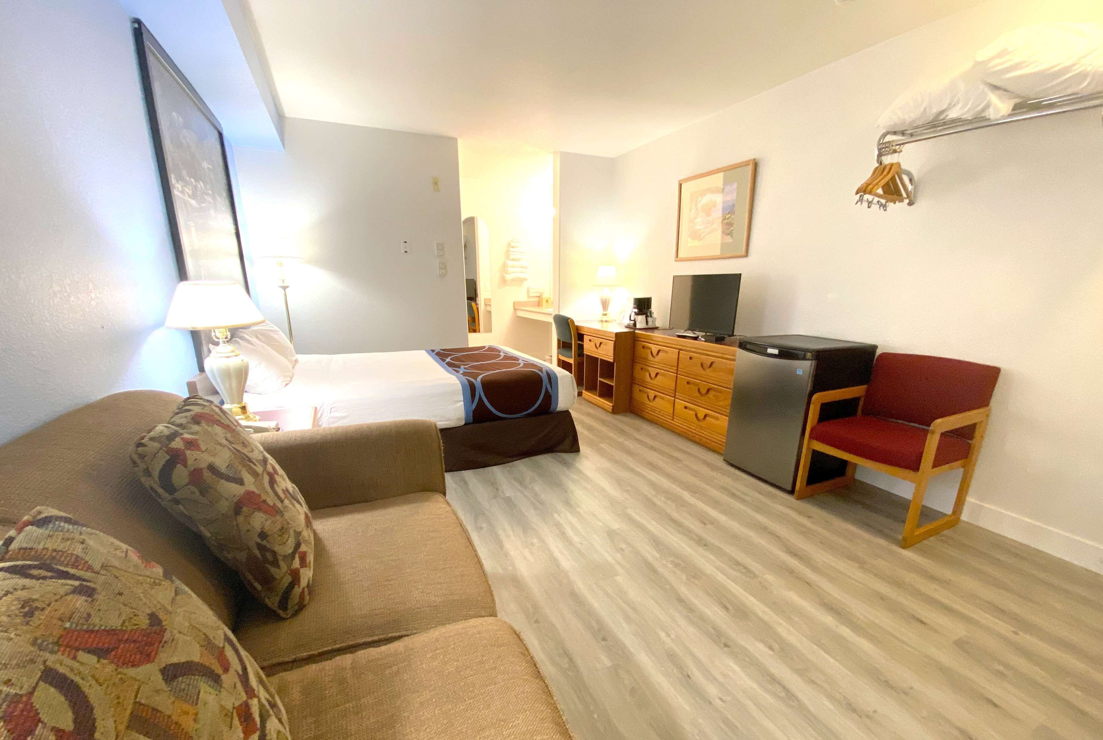 Una habitación de hotel con cama, sofá, escritorio con computadora y una silla.