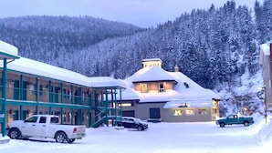 A hotel with a snow-covered exterior, a visible restaurant, and a parking area with vehicles.