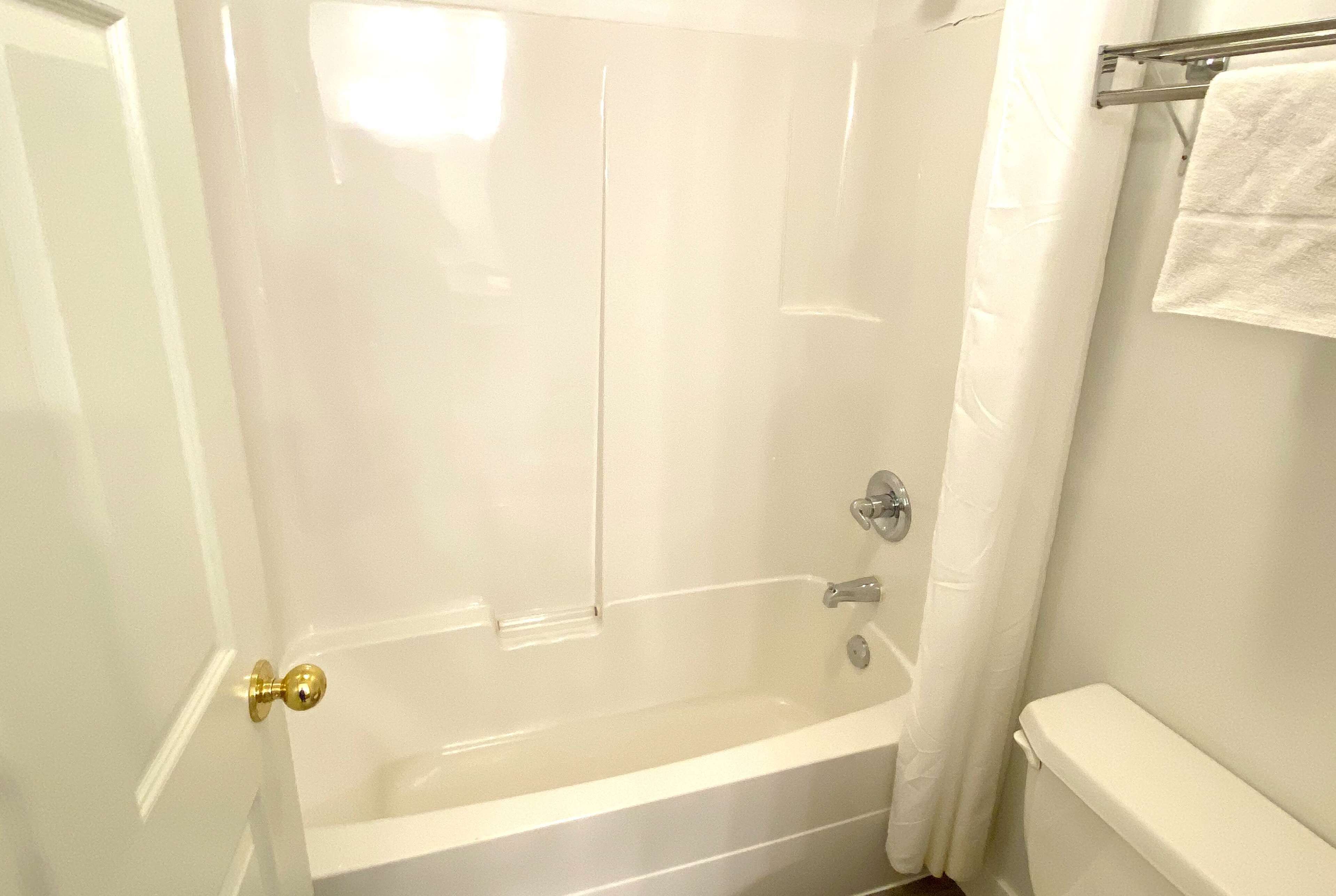 A white bathroom with a bathtub, a toilet, and a shower curtain.