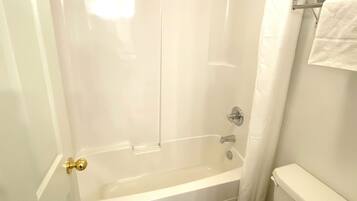 A white bathroom with a bathtub, a toilet, and a shower curtain.