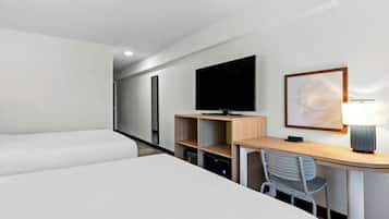 A hotel room with a bed, a desk with a chair, a television, and a lamp.