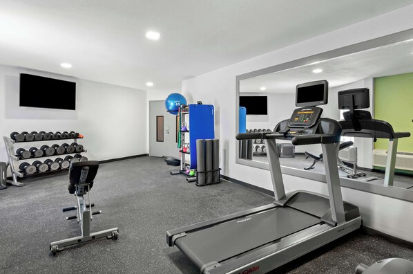 Une salle de sport équipée de tapis de course, d’haltères et d’autres appareils d’exercice.