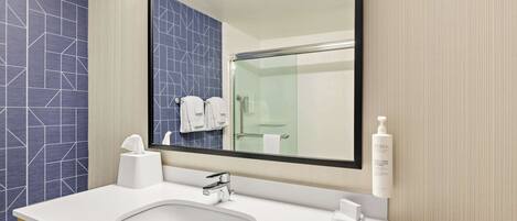 A modern bathroom with a white sink, a large mirror, and a glass shower enclosure.