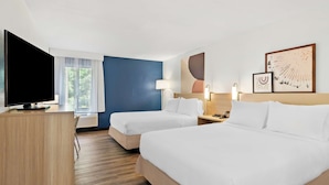 A hotel room with two beds, a desk, a TV, and artwork on the walls. - Spark by Hilton Winston-Salem University (Winston-Salem)