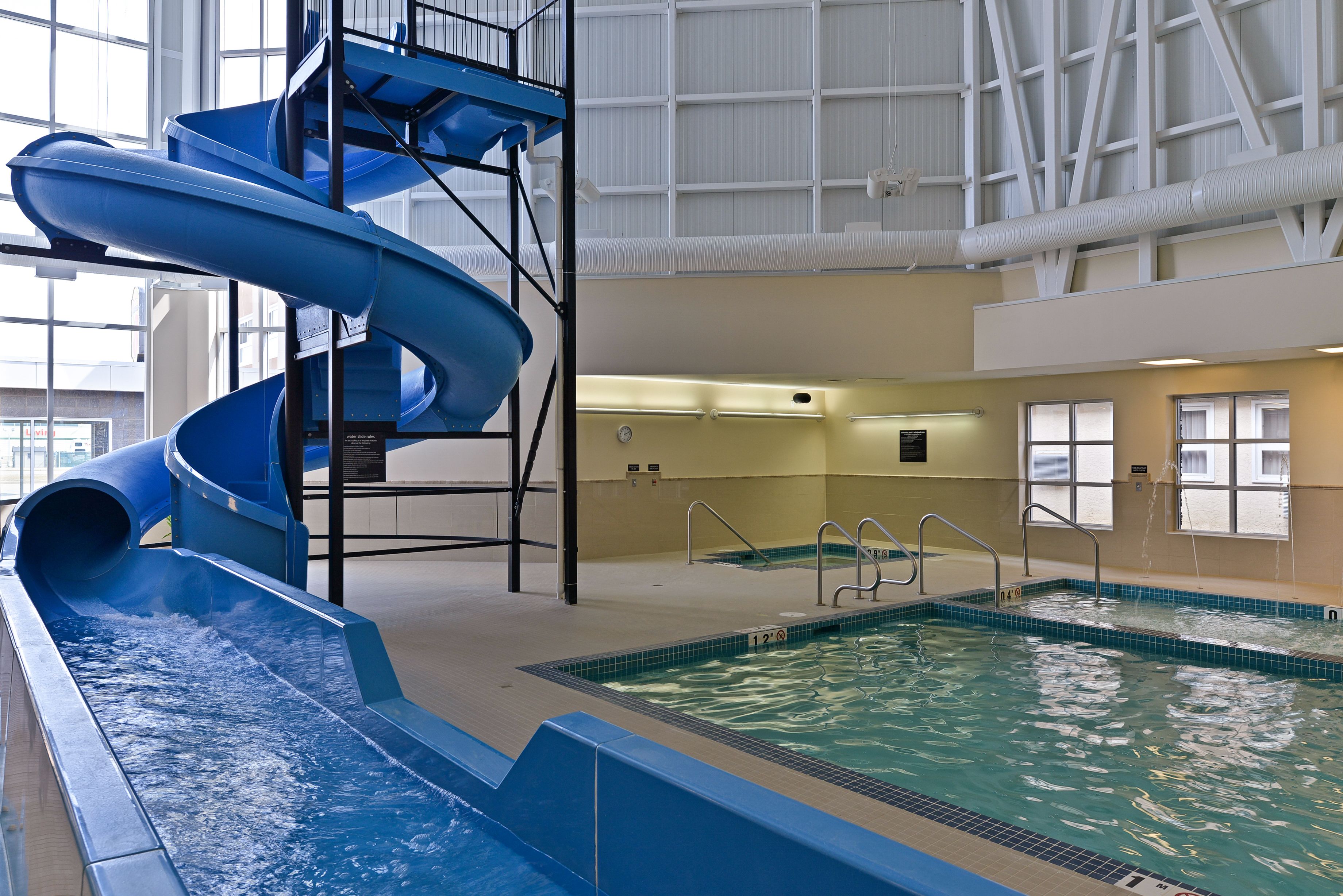 Una piscina interior con un tobogán de agua azul y una escalera de piscina.
