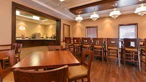 A conference room with a wooden table and chairs, a large mirror, and pendant lighting. - Siding 16 Lodge (Wetaskiwin)