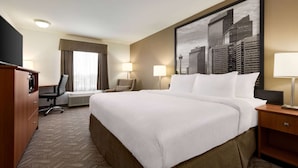 A hotel room with a large bed, a desk, a chair, a wardrobe, and a cityscape painting on the wall. - Super 8 by Wyndham Calgary Shawnessy Area (Calgary)
