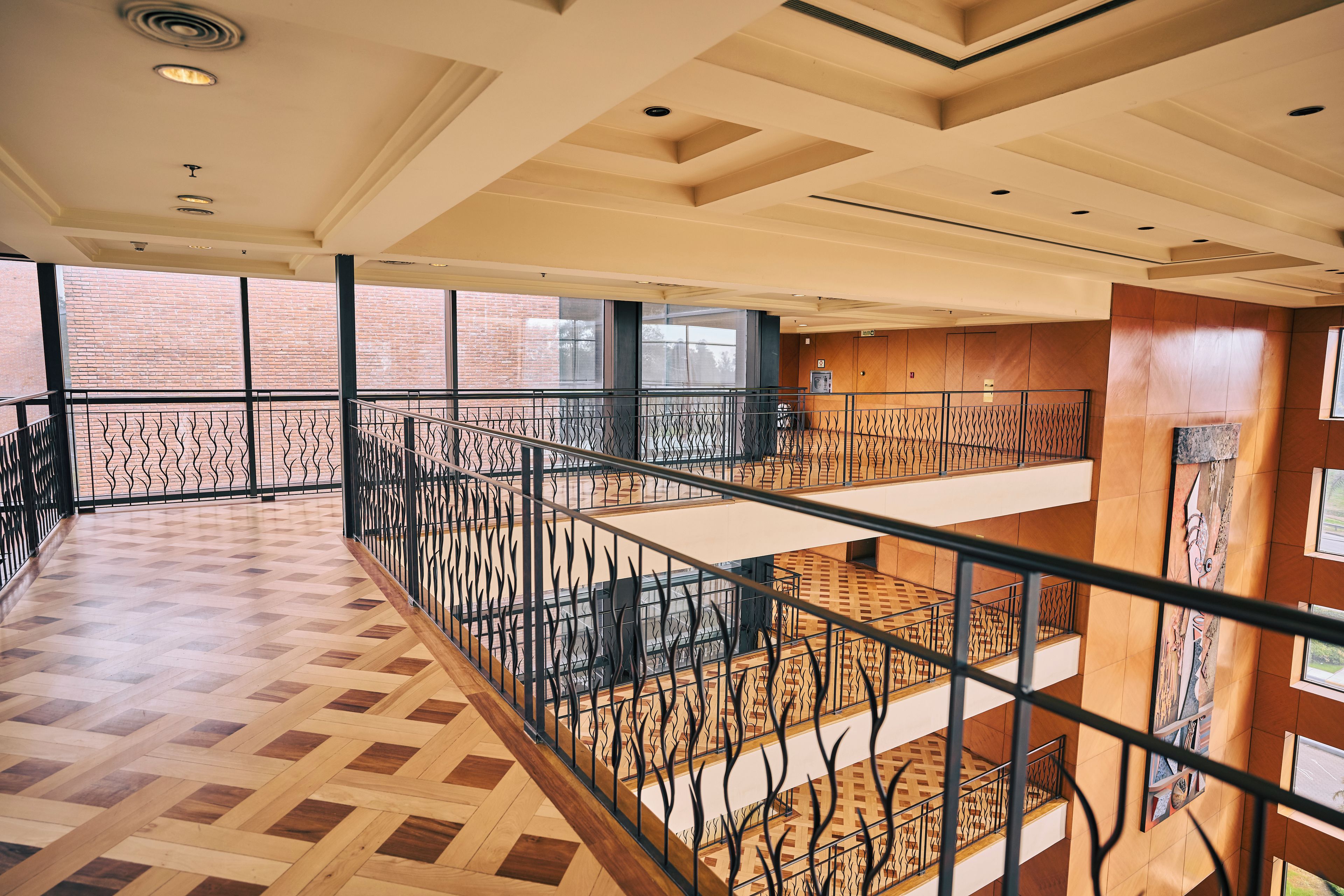 Un interior espacioso con piso de parquet de madera, un nivel entre piso y vistas a un edificio de ladrillo.