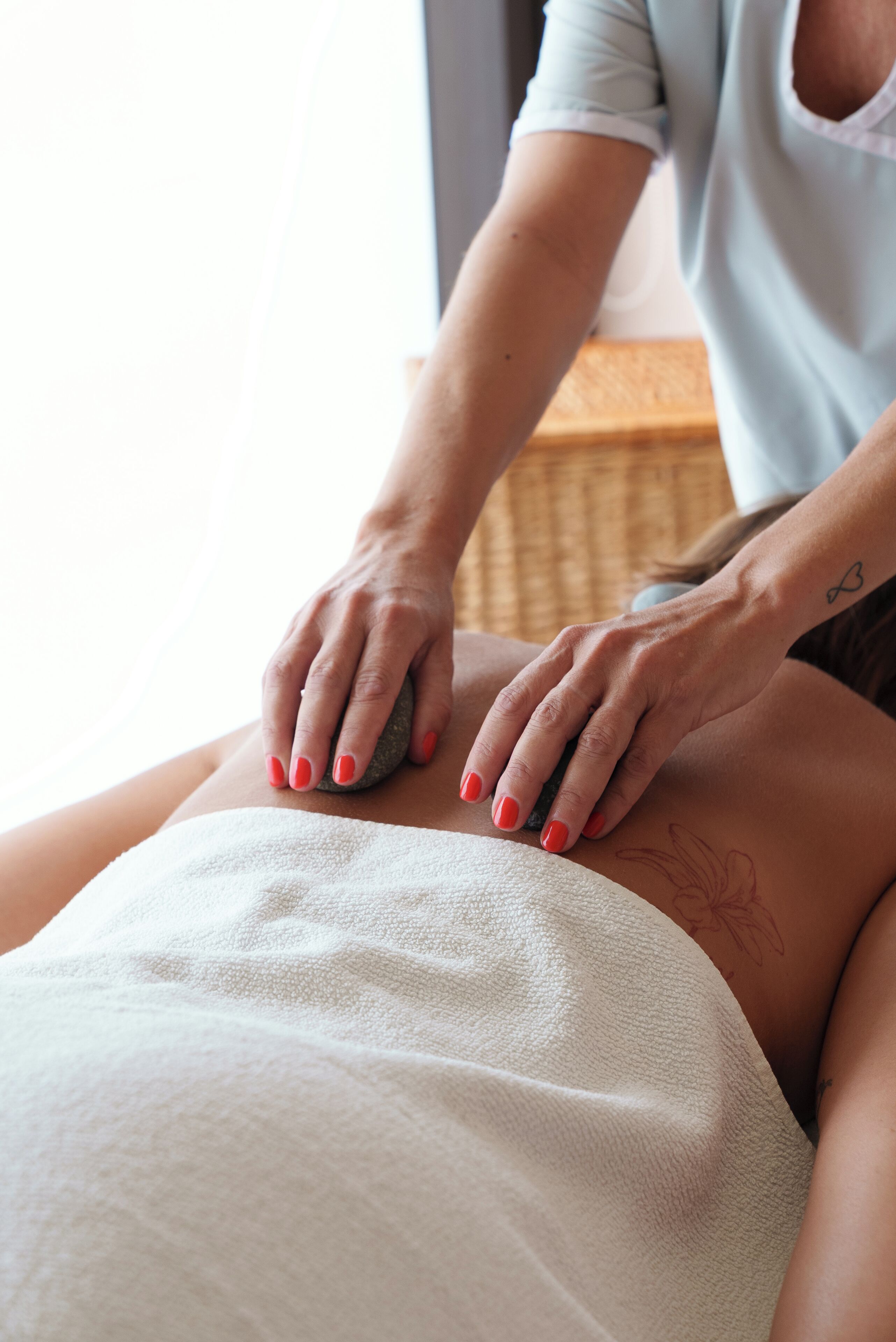 A person receiving a massage with a stone on their back.