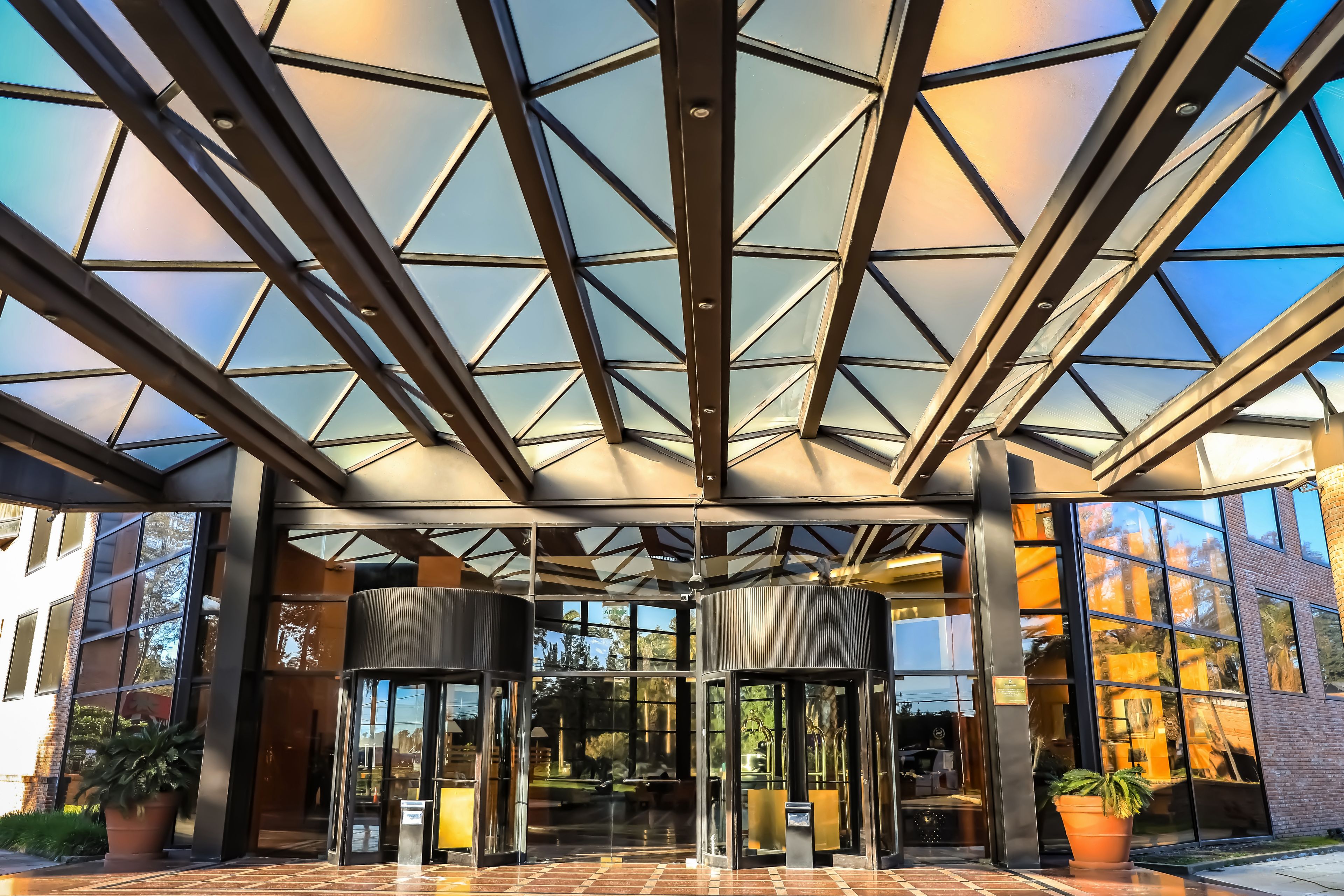 A modern building entrance with a glass roof and metal framework.