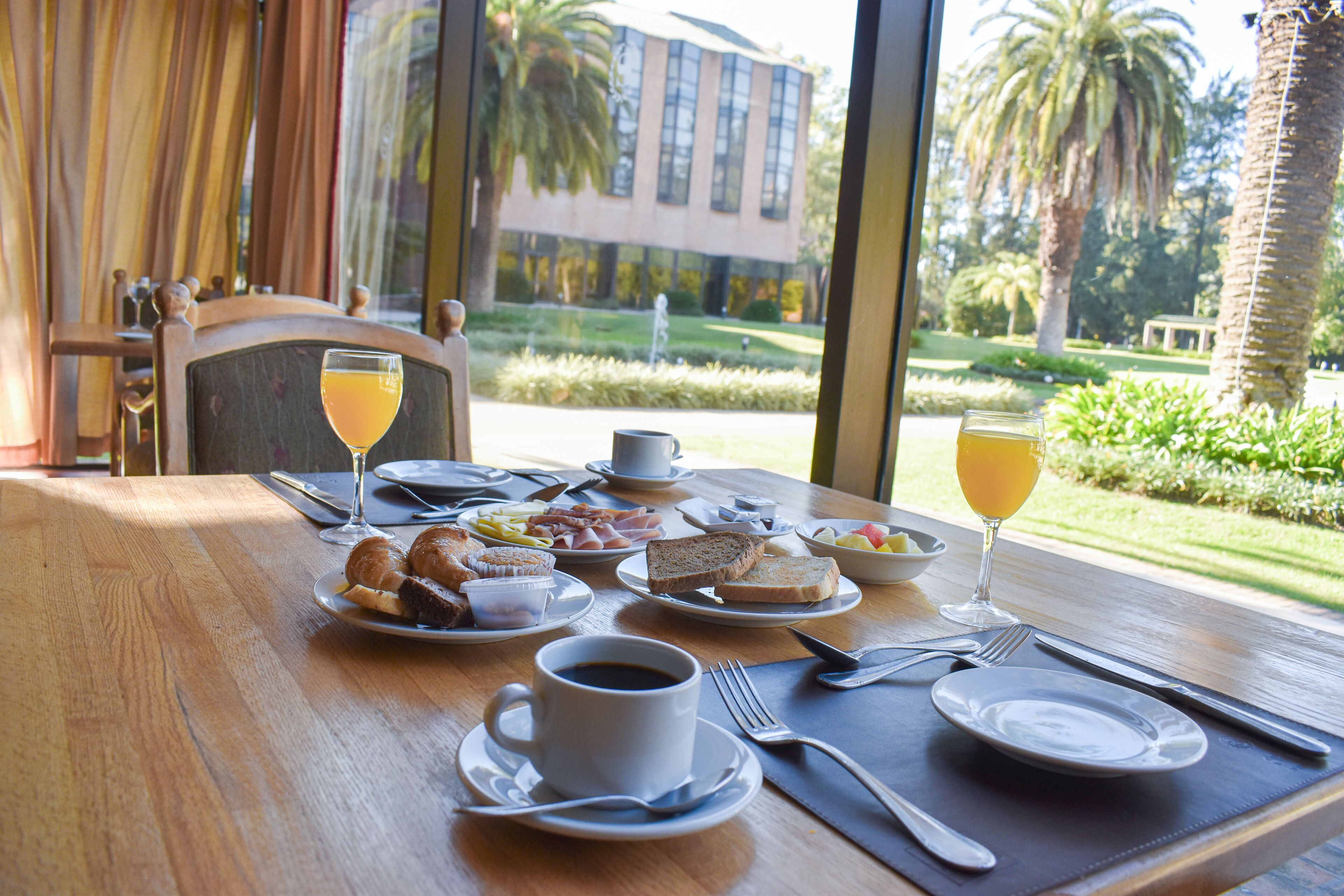 A breakfast table with croissants, toast, fruit, coffee, and orange juice.