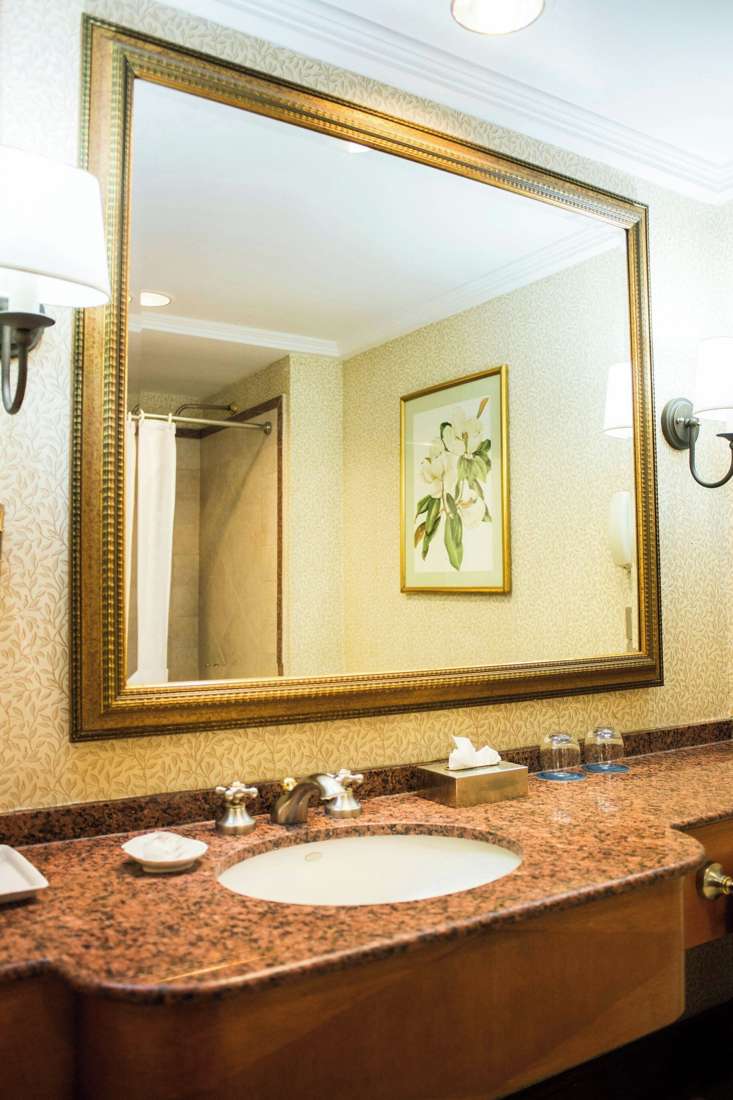 A bathroom with a large mirror, a sink, and a shower.