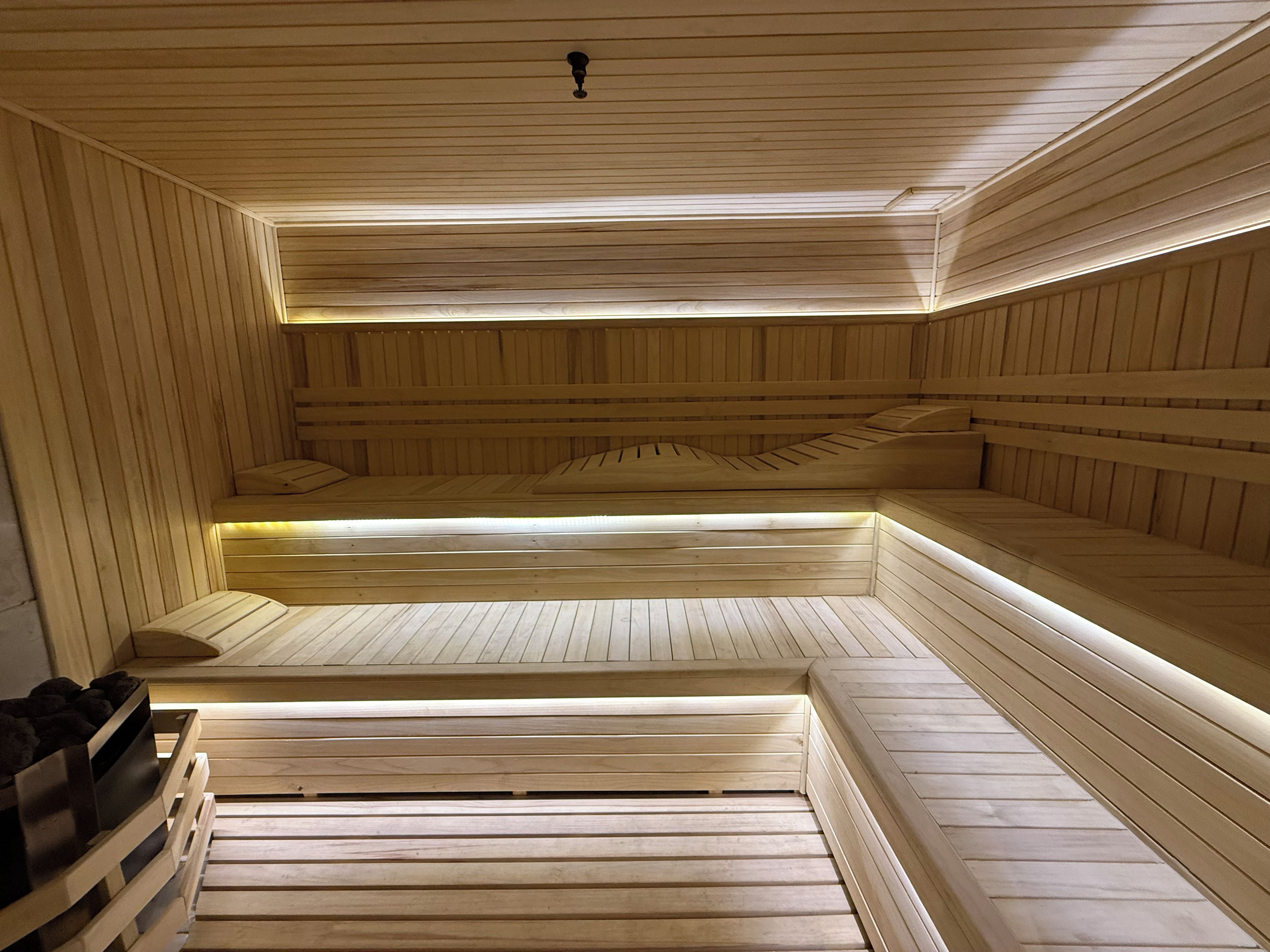 A sauna with wooden benches and benches, a ceiling with a vent, and a wall with a vent.