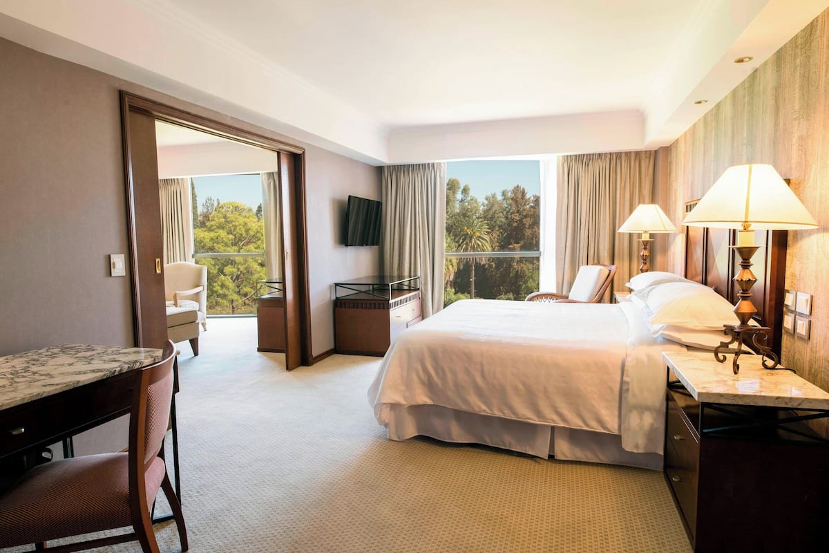 Ein Hotelzimmer mit Bett, Schreibtisch, Stuhl und Fernseher an der Wand.