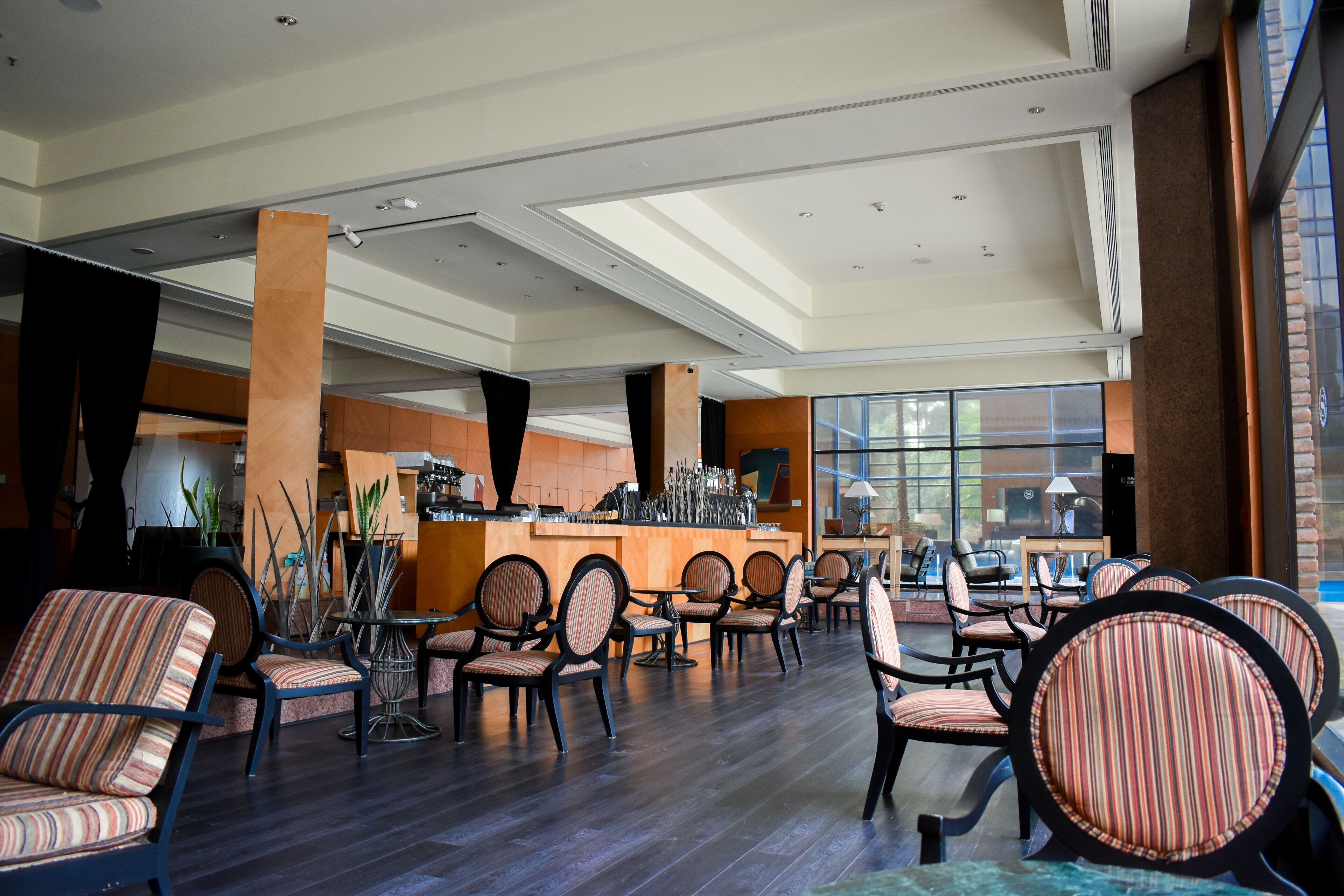 A spacious indoor seating area with multiple chairs and tables, a bar counter, and large windows allowing natural light.
