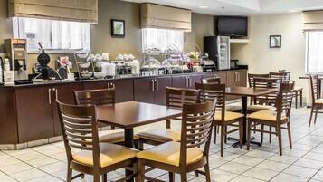 Un comedor de hotel con una barra de buffet, varias mesas y sillas.