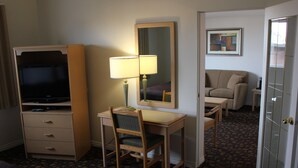 Habitación de hotel con escritorio, silla, televisor, lámpara y espejo.