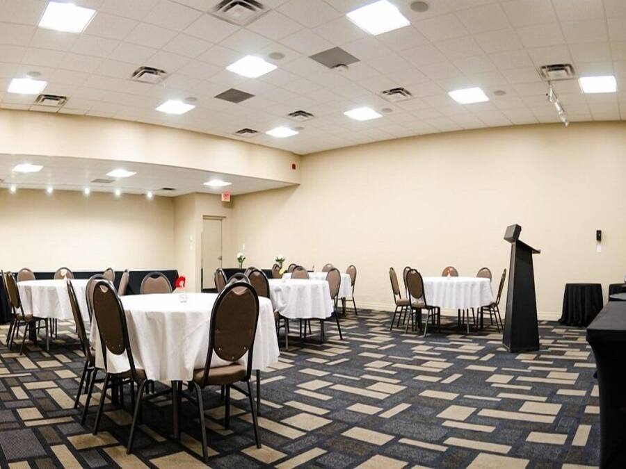 A conference room with multiple tables and chairs, a podium, and a carpeted floor.