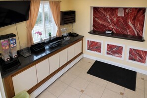 Una cocina con salpicadero de mármol, un televisor de pantalla plana y un ventanal con cortinas.