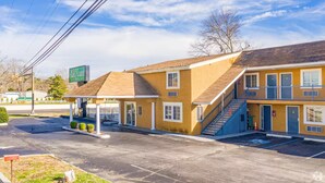 Un motel con un'area di parcheggio coperta, una scala per il piano superiore e un cartello con il nome.