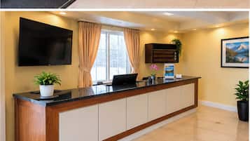 Una mesa de recepción con un televisor de pantalla plana, una computadora portátil y una planta.
