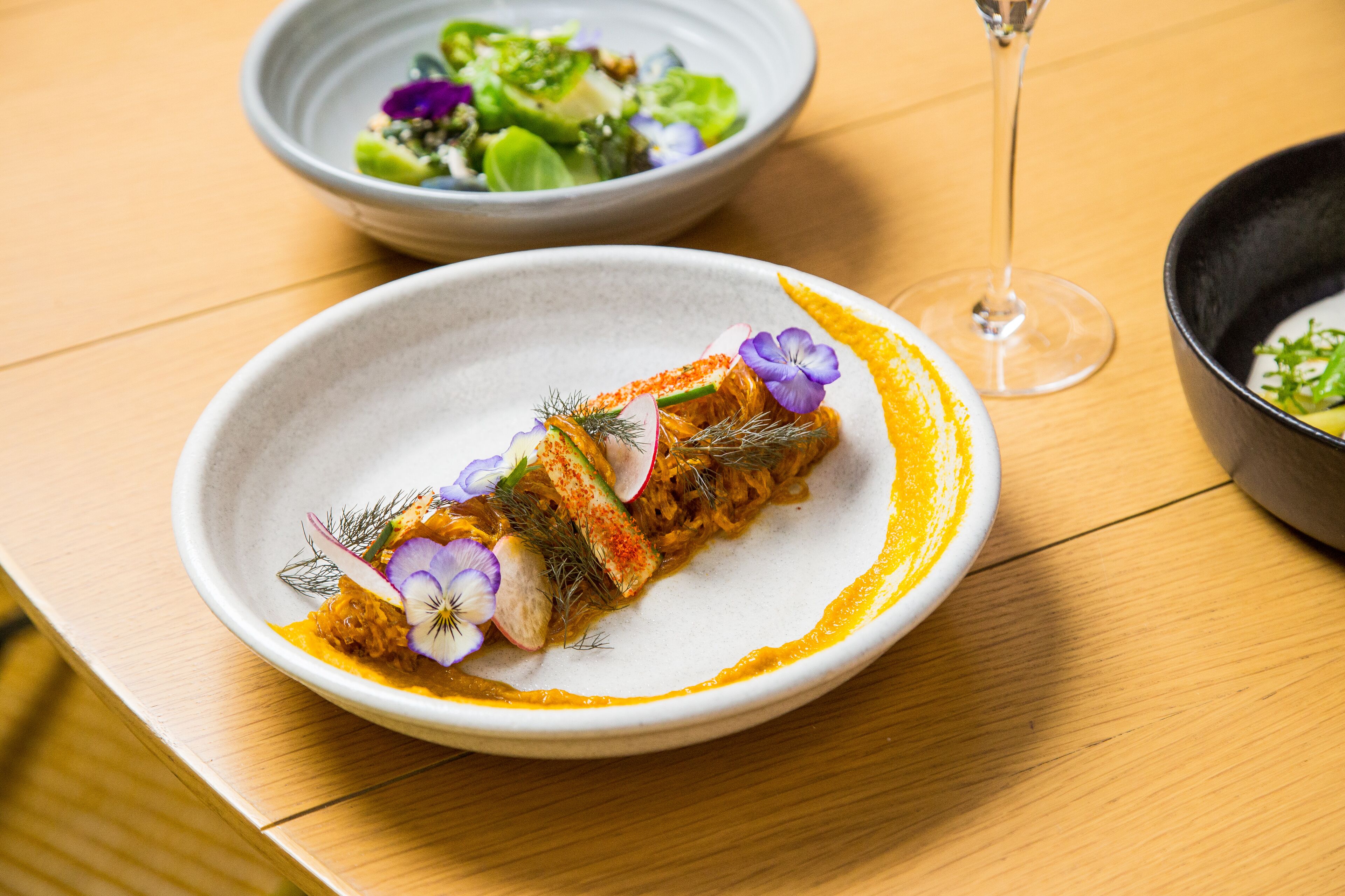 A plate of food with a glass of wine on a wooden table.