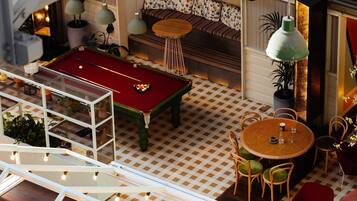 A billiards table, a sofa, a dining table with chairs, and a potted plant.