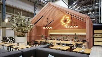 En modern restaurang med träbord, bekväma sittplatser och ett dekorativt träd.