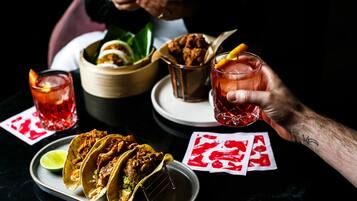 Una mesa de comedor con tacos, una bebida y cartas.