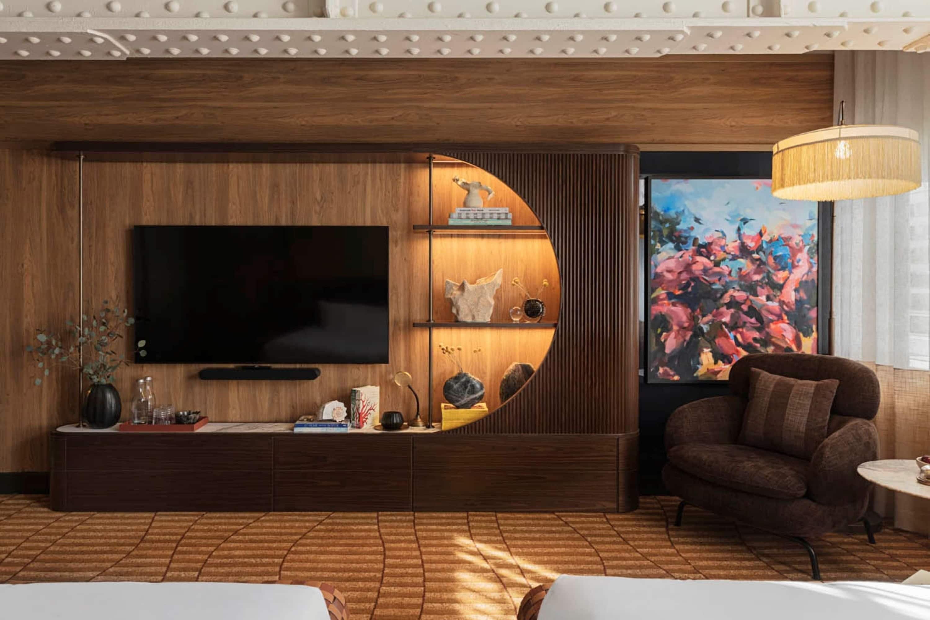 Un salon moderne avec un grand téléviseur à écran plat, une console ronde en bois, un canapé et un grand tableau.