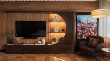 Un salon moderne avec un grand téléviseur à écran plat, une console ronde en bois, un canapé et un grand tableau.