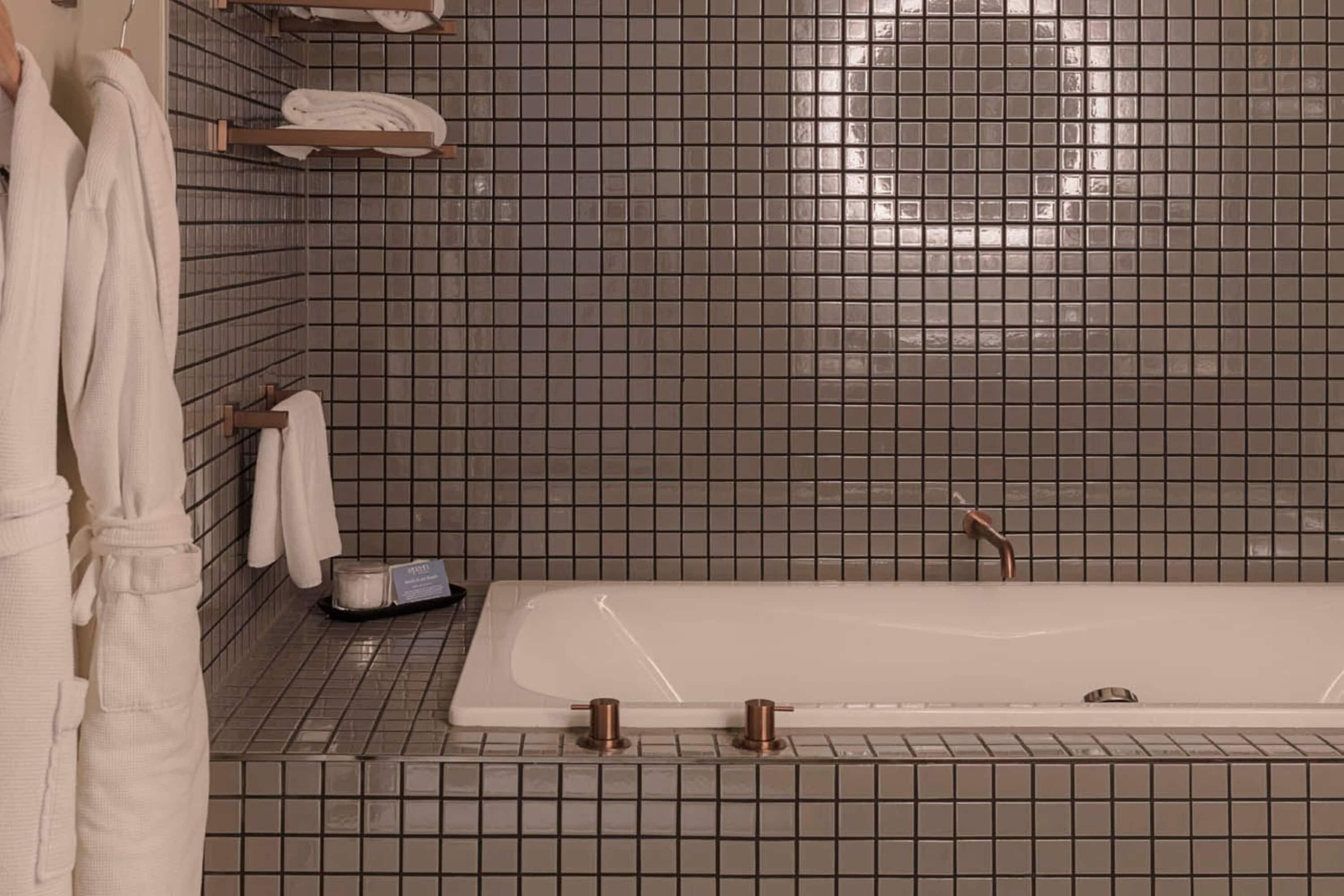 A bathroom with a bathtub, tiled walls, and towels on a rack.