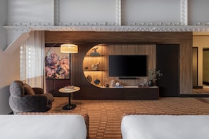 A modern hotel room with a large flat-screen TV, a round wooden console table, a sofa, and a patterned floor. - Ovolo Sydney Woolloomooloo, a Wyndham Hotel (Woolloomooloo)
