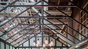 A modern interior with a glass table surrounded by purple chairs, a pink sofa, and a ceiling with exposed beams and hanging lights. - Ovolo Sydney Woolloomooloo, a Wyndham Hotel (Woolloomooloo)
