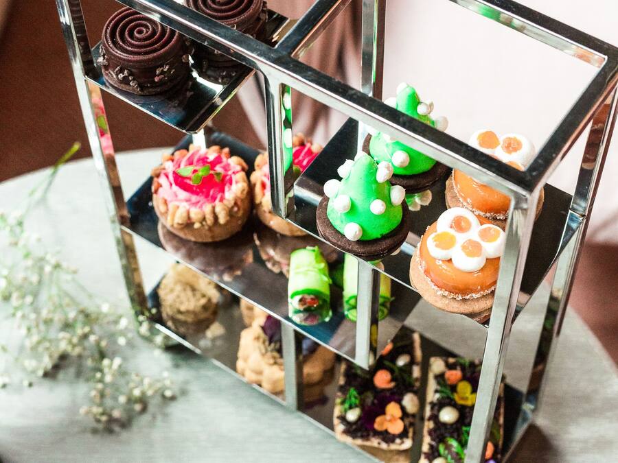 Una exposición de postres con diversos pasteles en un soporte de metal.