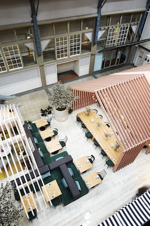 A multi-level indoor space with seating areas, tables, and a central plant. - Ovolo Sydney Woolloomooloo, a Wyndham Hotel (Woolloomooloo)