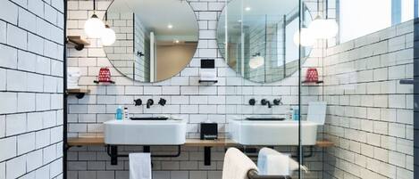 A modern bathroom with two sinks, large mirrors, and a glass shower enclosure.