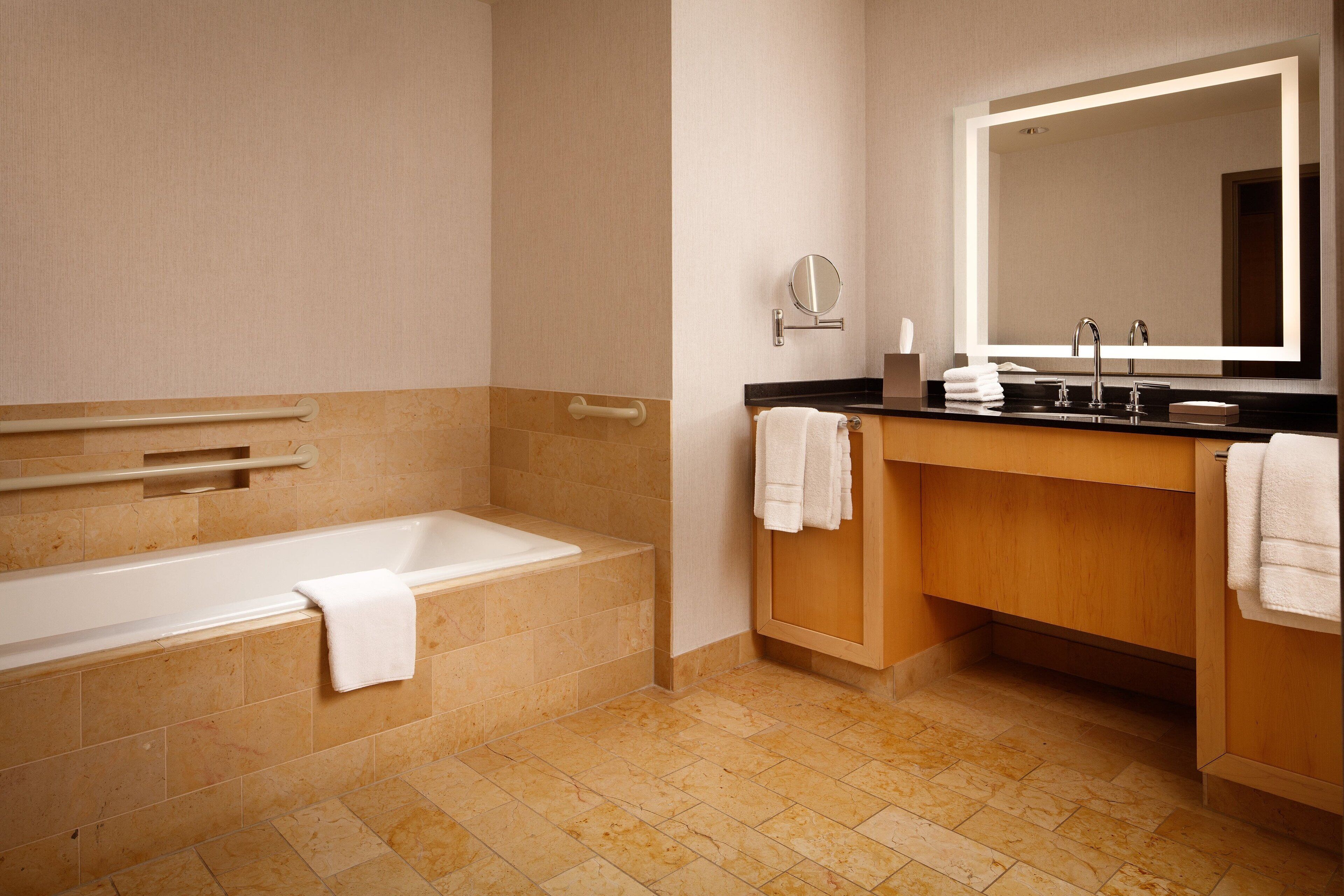 A modern bathroom with a bathtub, a sink with a mirror, and a vanity with a towel rack.