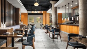 A modern restaurant interior with high tables, chairs, and a central bar area. - The Westin St. Louis (St. Louis)