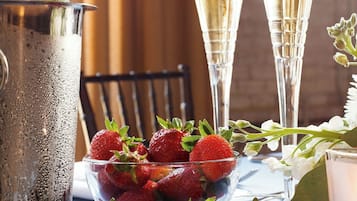 Een fles champagne, twee glazen en een schaal aardbeien op een tafel.