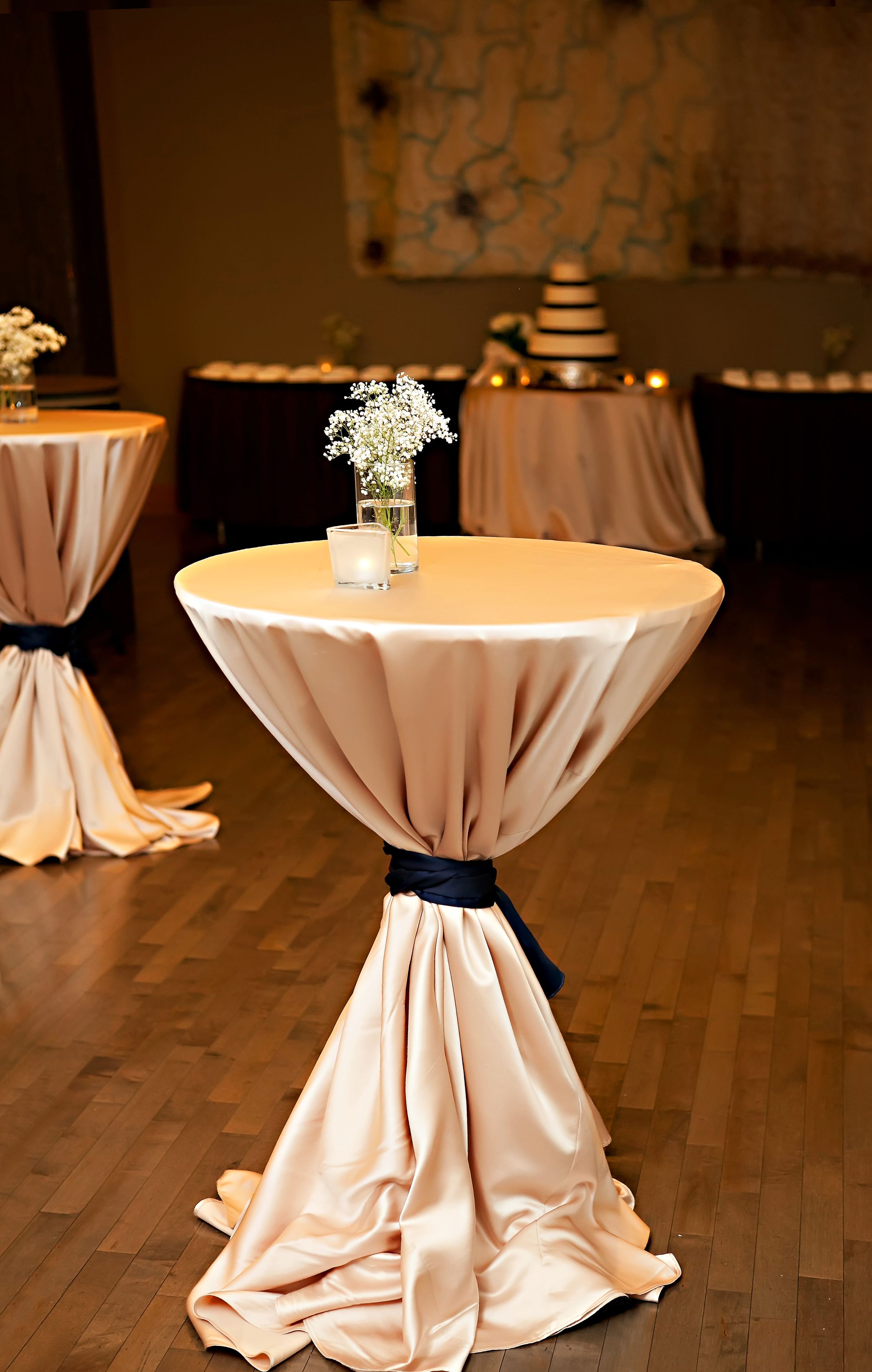 A round table with a draped tablecloth and a candle centerpiece.