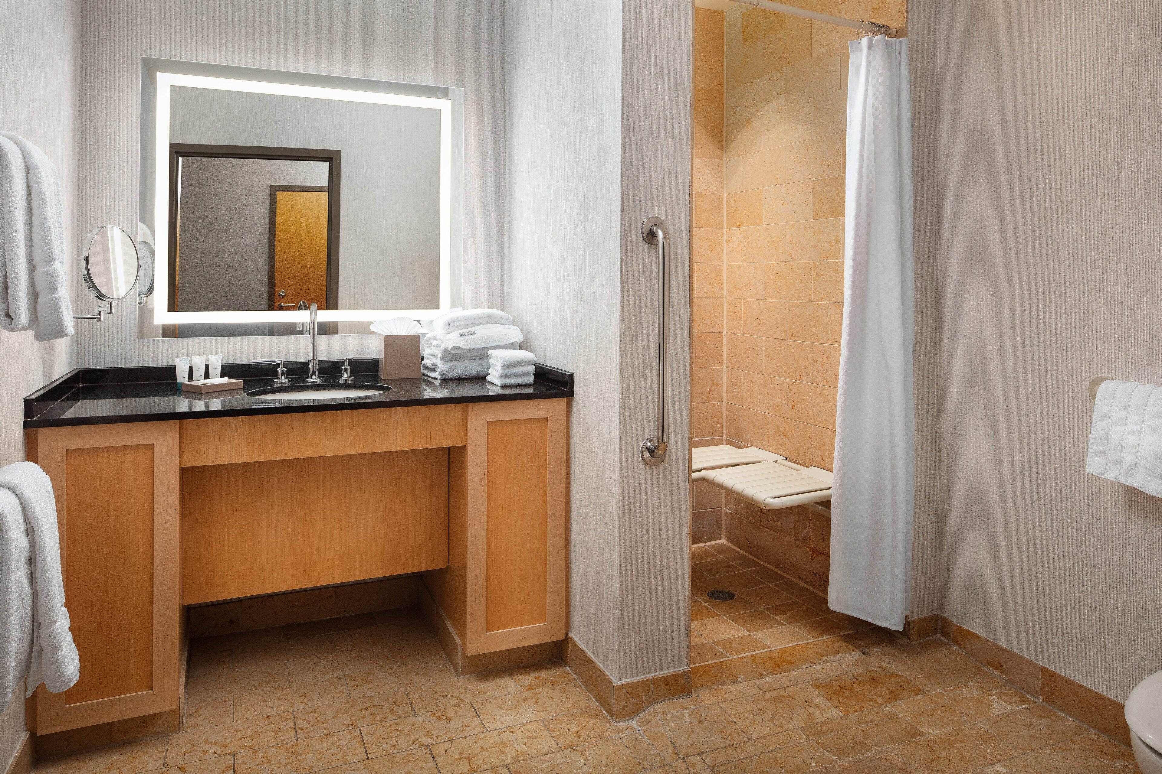 A modern bathroom with a vanity, sink, mirror, and shower area.
